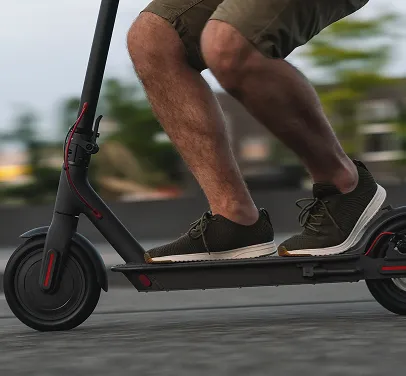 Personne en baskets sur une trottinette électrique en ville