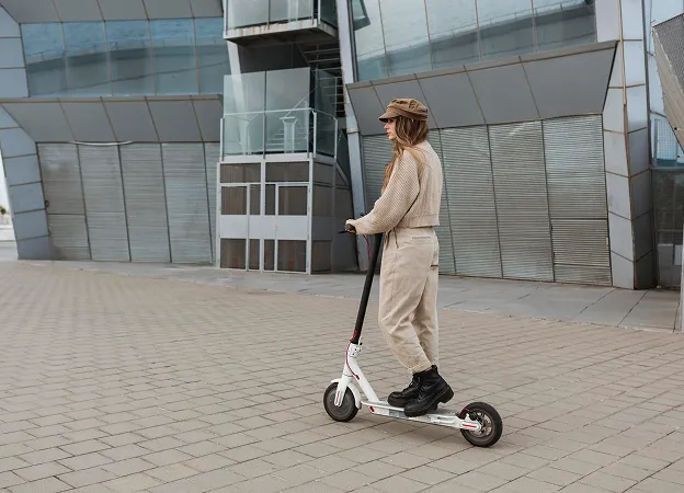 Personne avec une trottinette électrique devant un bâtiment moderne